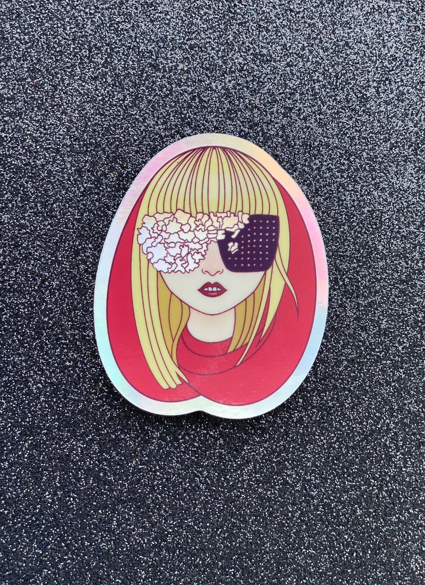 Illustrated sticker of Lady Gaga wearing a red hood and black and irridescent glasses against a black glitter background