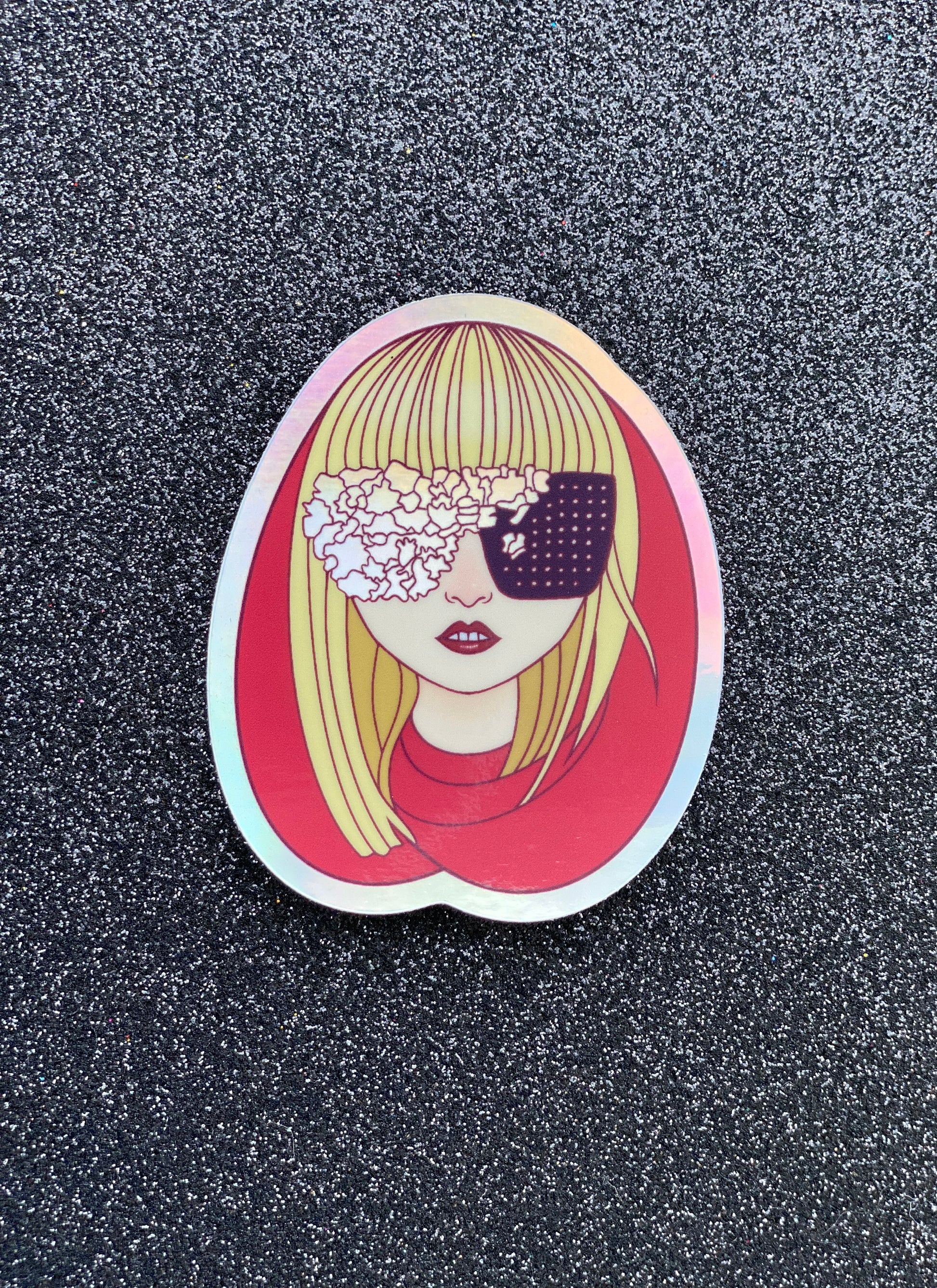 Illustrated sticker of Lady Gaga wearing a red hood and black and irridescent glasses against a black glitter background