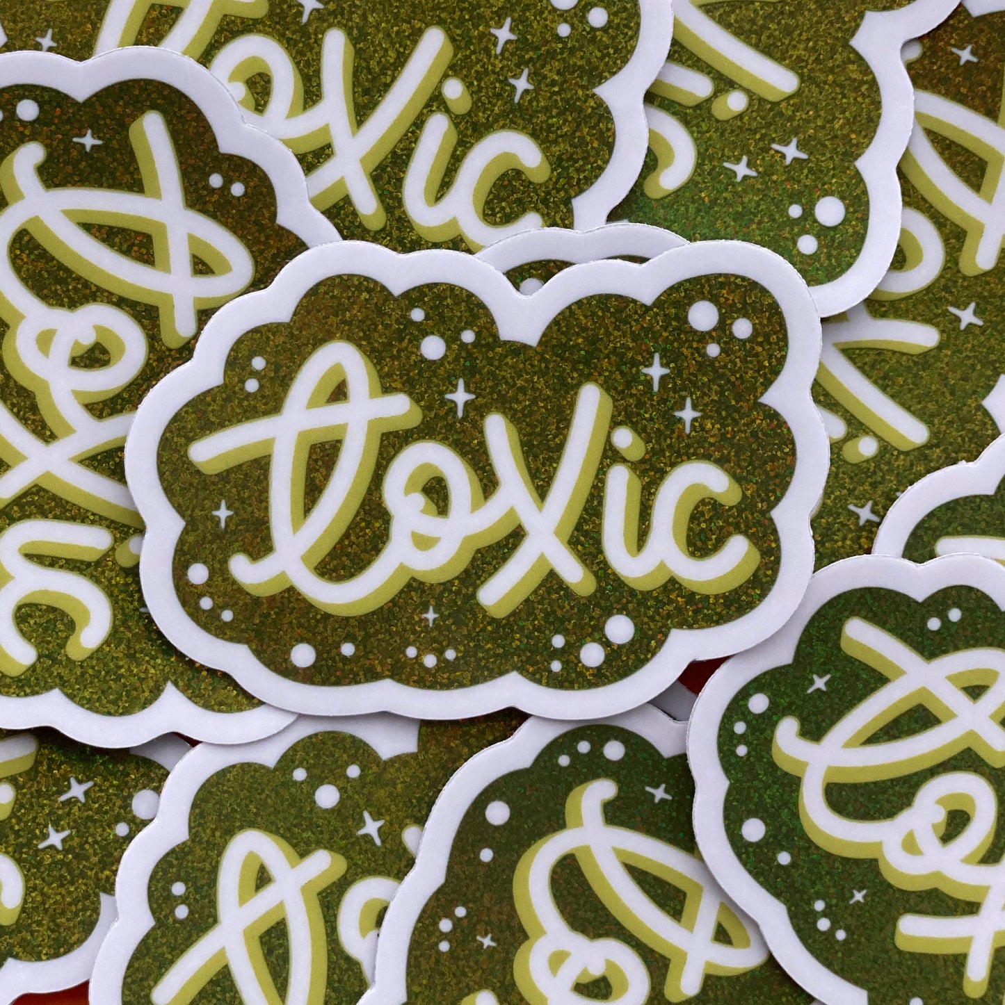 A pile of green glitter stickers that say "Toxic" in script.