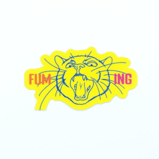 A photo of a neon yellow sticker on a white background. Sticker features an illustration of a cat screaming and the word "Fuming." One whisker is cut off, making this a b-grade