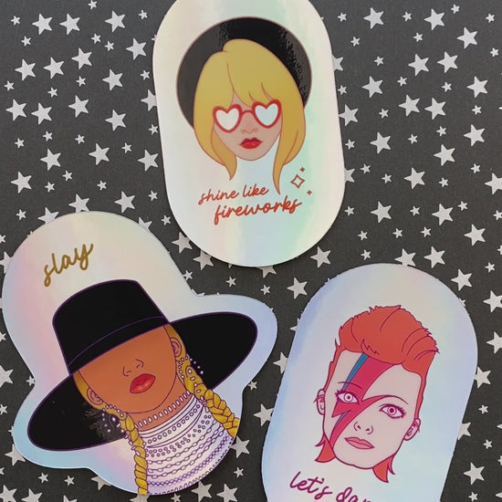 A video of holographic stickers of Taylor Swift, David Bowie, and Beyoncé. The stickers move to show off the holographic effect of the vinyl.