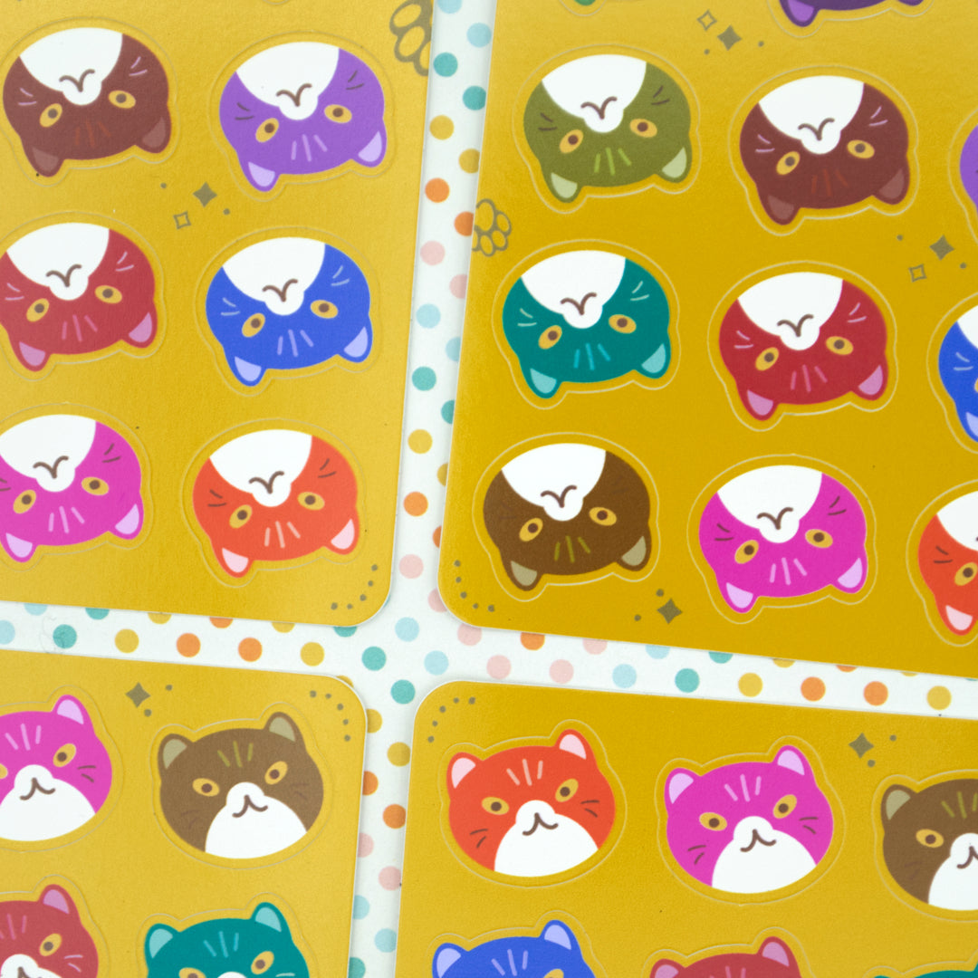 Four yellow sticker sheets at different angels against a pink, yellow, green and light blue polka dot background.