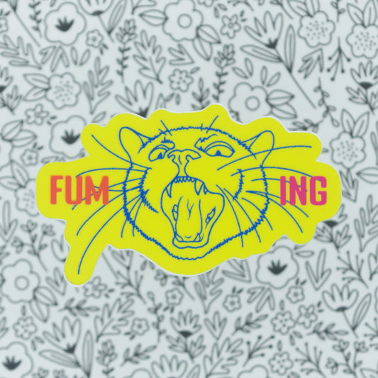 A neon yellow sticker with the word fuming broken into two on either side of a screaming cat head.