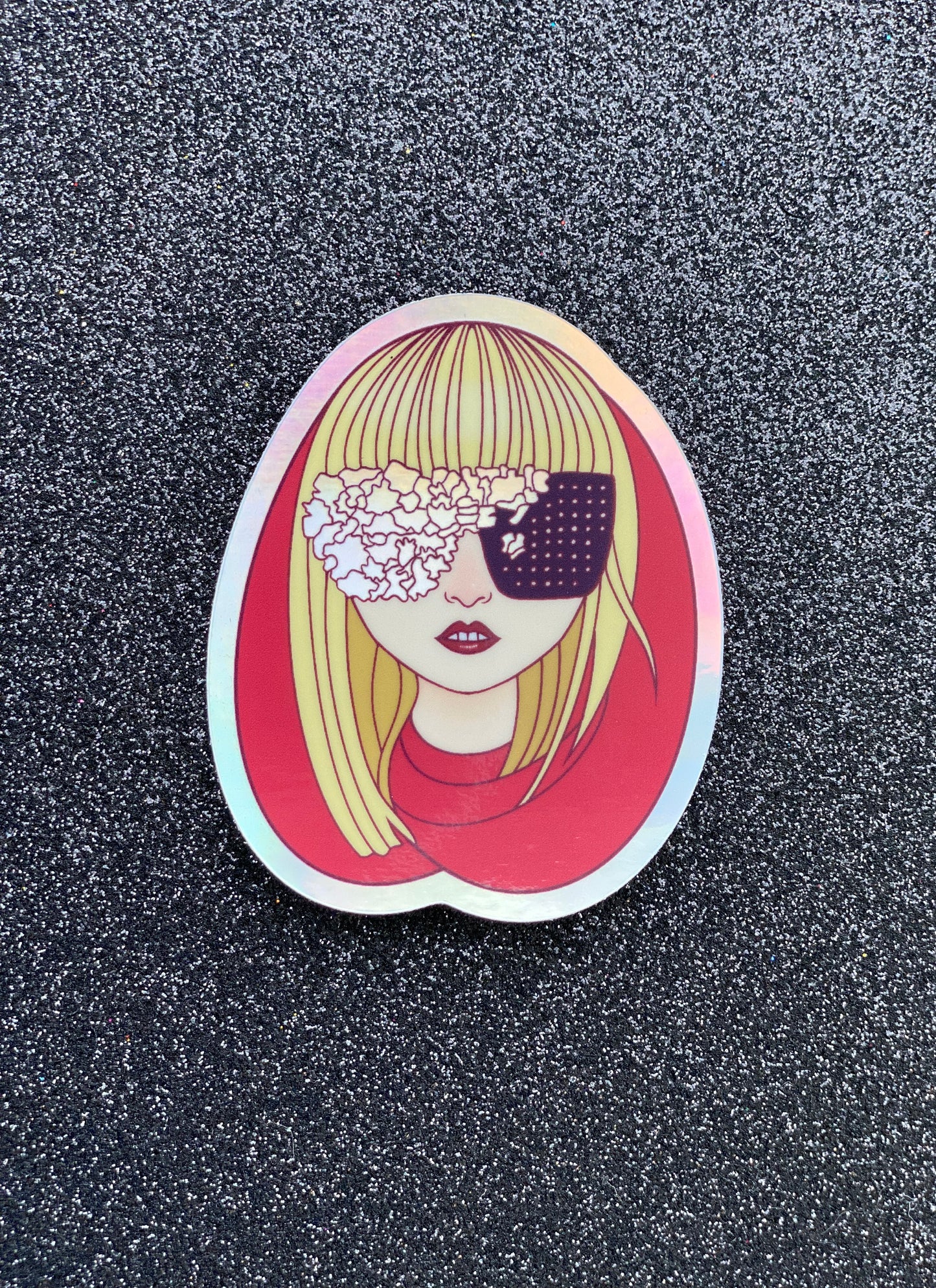 Illustrated sticker of Lady Gaga wearing a red hood and black and irridescent glasses against a black glitter background