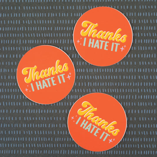 Three orange stickers with the words "Thanks I hate it" in yellow and light blue text.