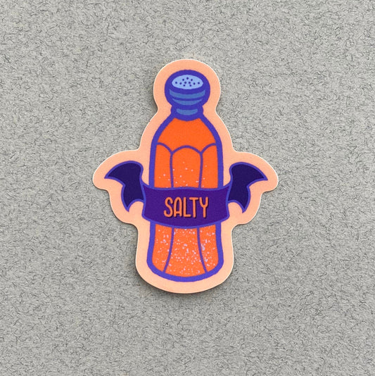 A peach vinyl sticker with an illustration of a salt shaker and a banner that says "Salty".