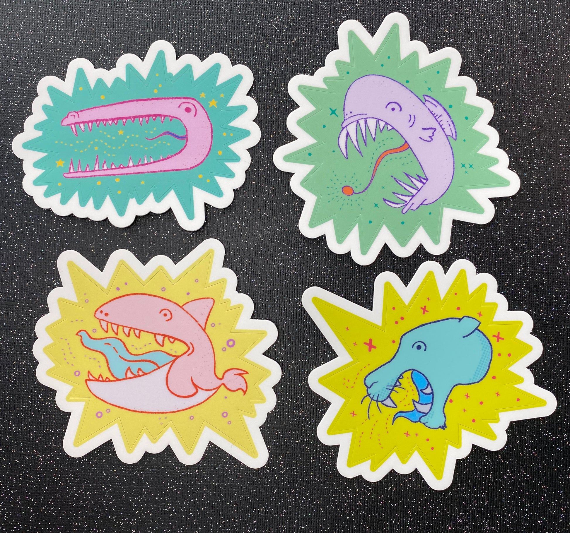 A photo of all four Anxiety Animals stickers against a black glitter background. 