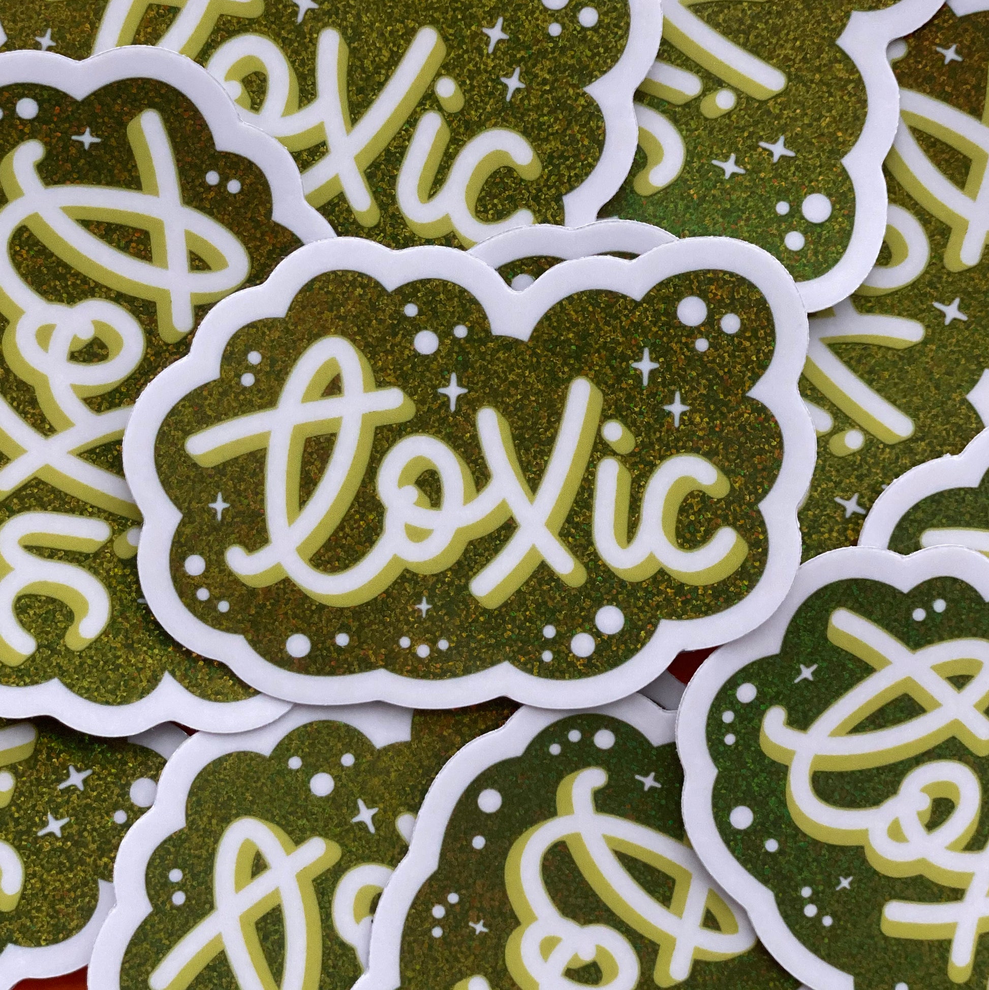 A pile of green glitter stickers that say "Toxic" in script. 